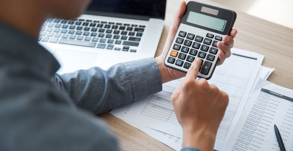 Gros plan sur une calculatrice posée sur un bureau avec des documents partiellement visibles en arrière-plan